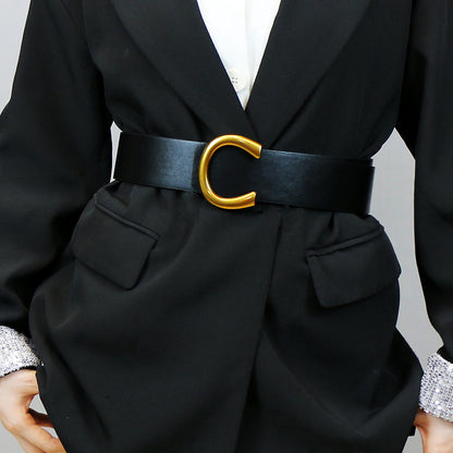 Ceinture large à boucle fer à cheval géométrique avec un tailleur et une jupe