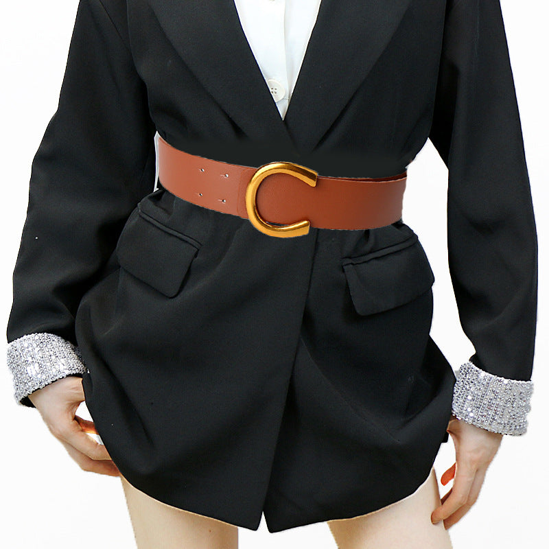 Ceinture large à boucle fer à cheval géométrique avec un tailleur et une jupe