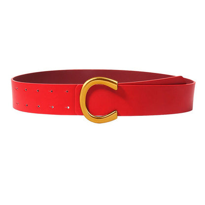 Ceinture large à boucle fer à cheval géométrique avec un tailleur et une jupe